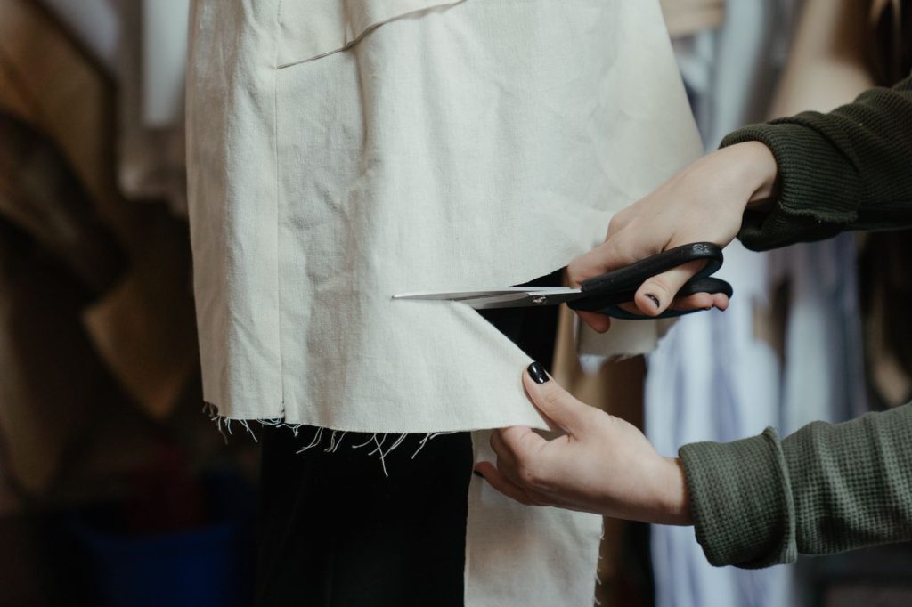 Mains découpant un tissu dans un atelier de couture