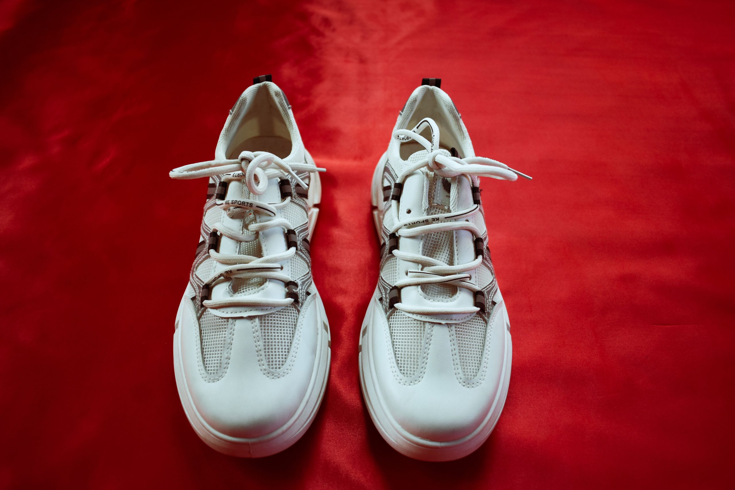 Paire de baskets blanches tendance sur fond rouge
