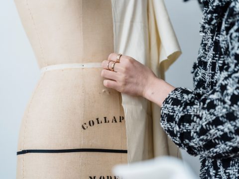 Mains ajustant un vêtement en atelier de haute couture