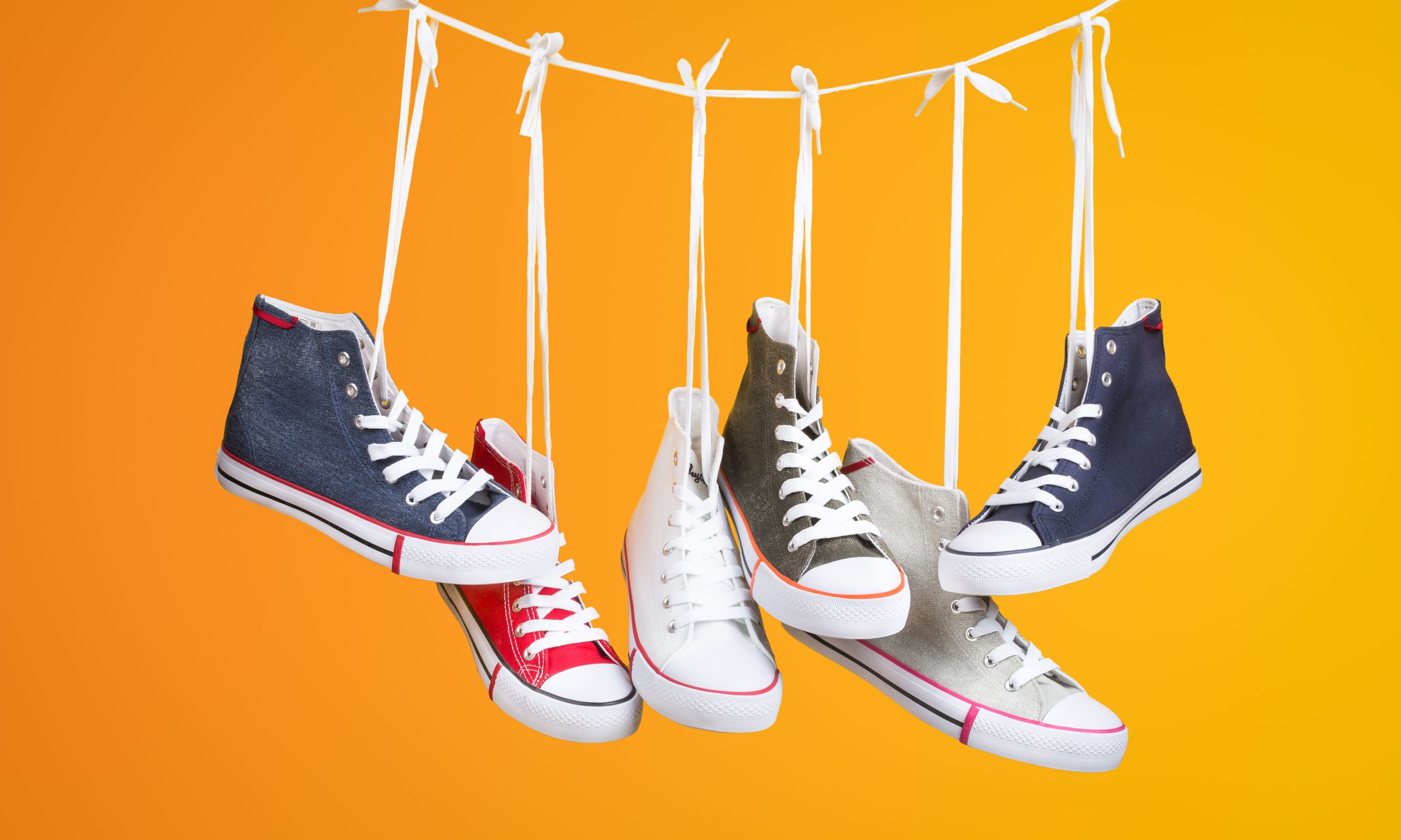 Paire de baskets colorées suspendues sur fond orange