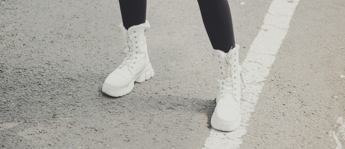 Jambes portant des bottes hautes blanches avec un jean