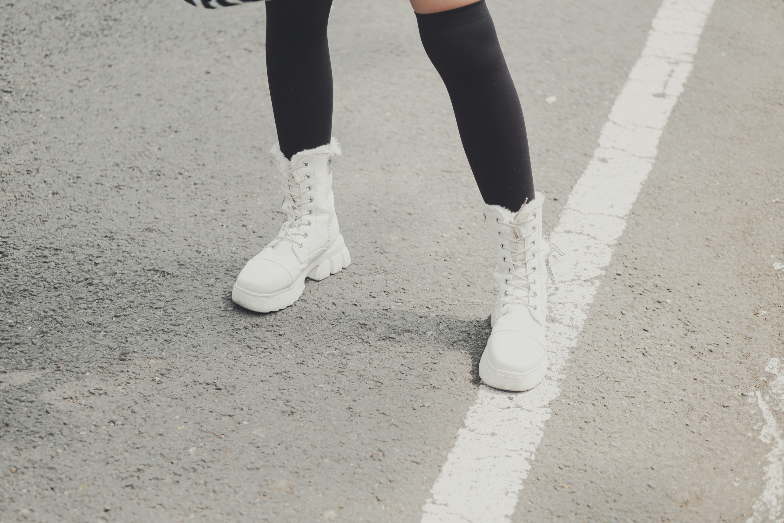 Jambes portant des bottes hautes blanches avec un jean