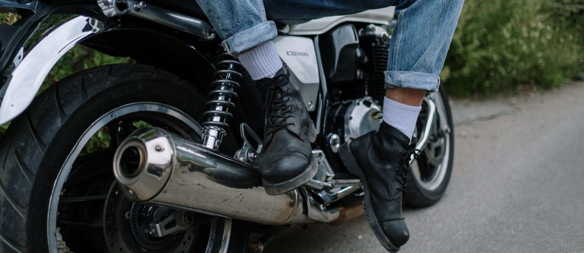 Bottes biker en cuir noir, pieds posés sur une moto, style rock