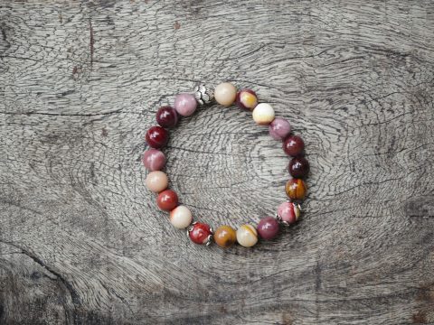 bracelet de perles rondes en pierre naturelle posé sur une planche de bois